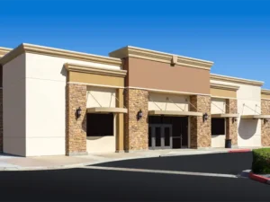 Empty commercial building with stone and beige facade under a clear blue sky. commercial water damage restoration