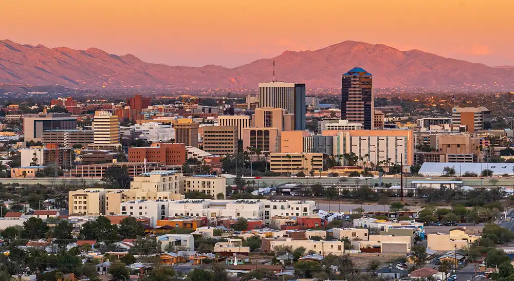 City skyline with mid-rise buildings and mountains in the background at sunset. water damage restoration in Tucson